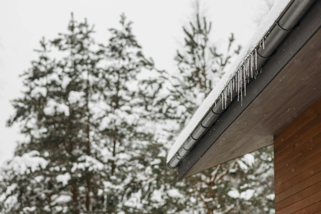 an eavestrough ready for replacement with icicles hanging off the sides in winter